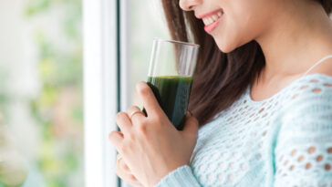 Smiling woman holding green drink.
