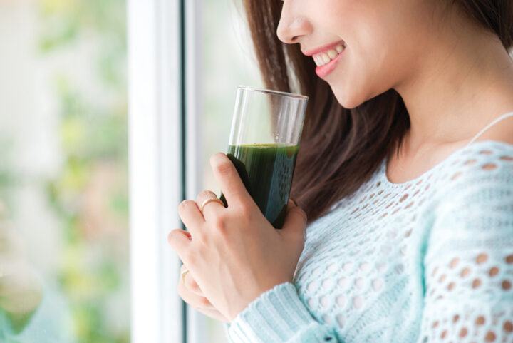 Smiling woman holding green drink.