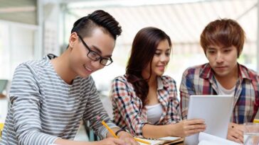 A young woman and two young men studying together.
