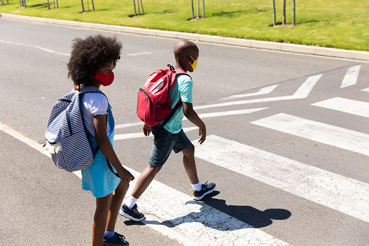 Two kids wearing face masks crossing the road - Central Florida Lifestyle