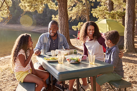 family sitting outside eating in nature in the summer