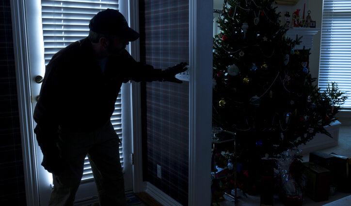 This photo illustrates a burglary or thief breaking into a home at night through a back door during the Christmas Holiday Season.