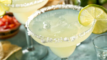 Delicious tequila and lime margaritas on an outdoor table with tortilla chips