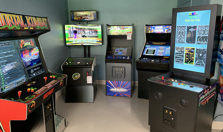Photo of multiple game machines inlcuding Mortal Kombat, Golden Tee and Arcade Legends inside a man cave.