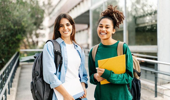 Two College Student female friends smiling ready for classes at the University campus
