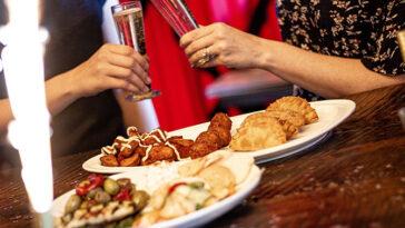 Photo of people out eating at a restaurant and toasting a glass.