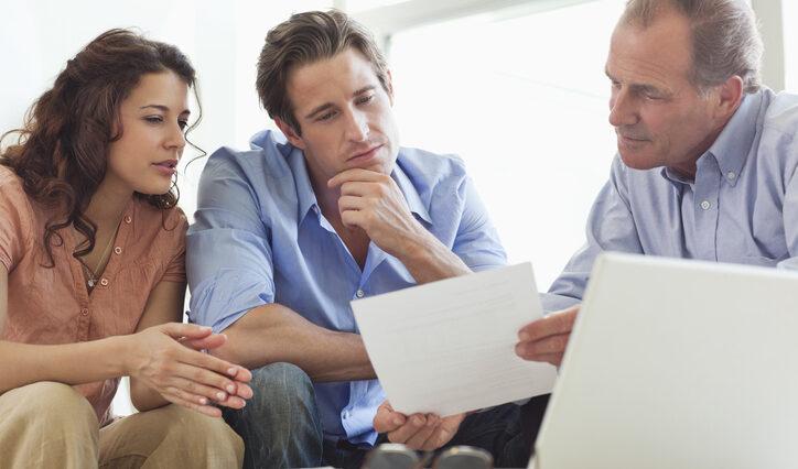 Couple going over paperwork with financial advisor to achieve financial success.
