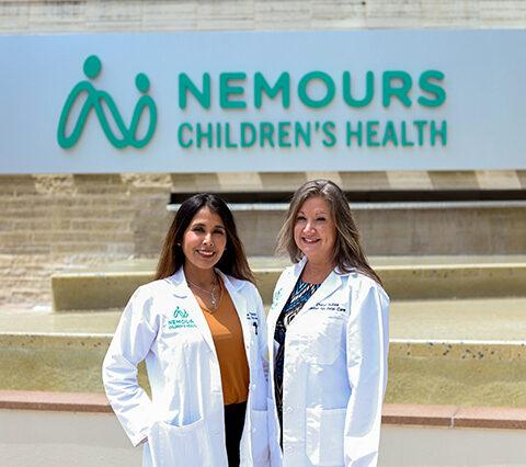 Photo of Dr. Taboada and Kubas, the maternal fetal medicine team standing in front of the Nemours Children's Hospital sign.