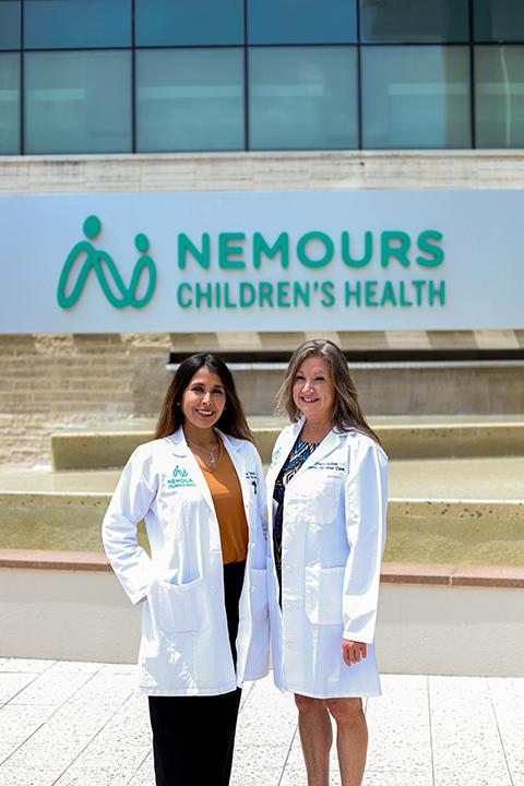 Photo of Dr. Taboada and Kubas, the maternal fetal medicine team standing in front of the Nemours Children's Hospital sign.
