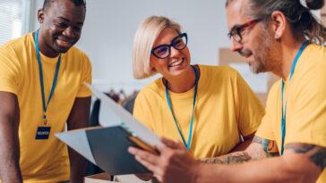 Group of diverse people working in charitable foundation. Happy volunteer separating donation stuff. Social workers making check list of the thins that are done. Copy space. Working as a team. giving guide.