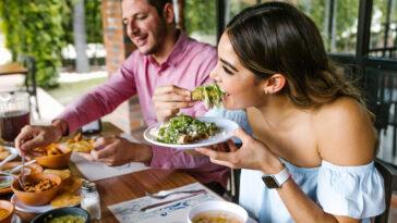 young latin woman eating mexican tacos on a restaurant terrace, new eateries in Orlando.