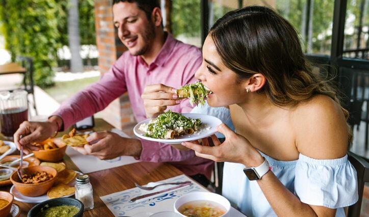 young latin woman eating mexican tacos on a restaurant terrace, new eateries in Orlando.