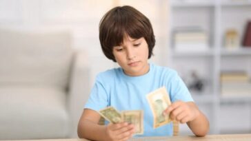 Boy counting money notes at table