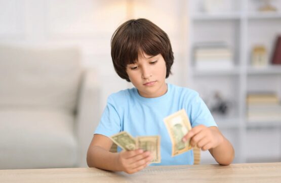 Boy counting money notes at table