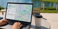 Person using a laptop outdoors in Lake Nona while viewing a Google Maps search of the Lake Nona region, with the lake and modern buildings in the background.