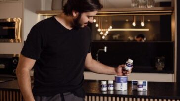 A woman reading a supplement label in her kitchen