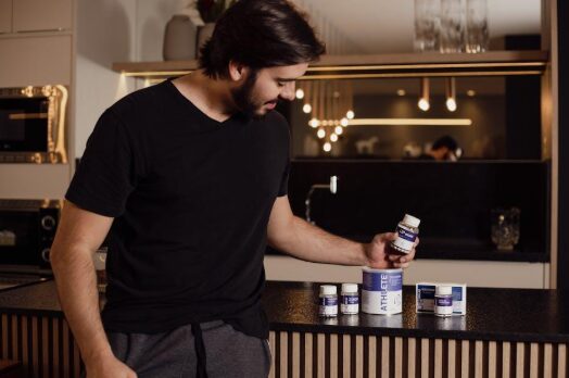 A woman reading a supplement label in her kitchen